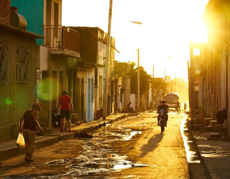 People motorcycling and walking in an alley things to do in Trinidad Cuba