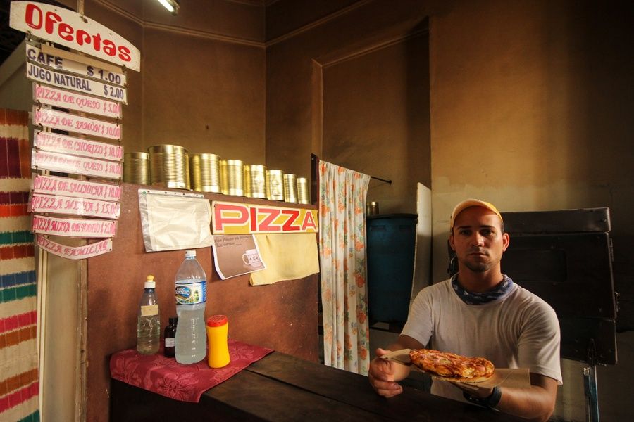 Man eating Pizza Cubana cheap food in Cuba