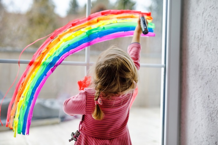 Girl painting rainbow on window